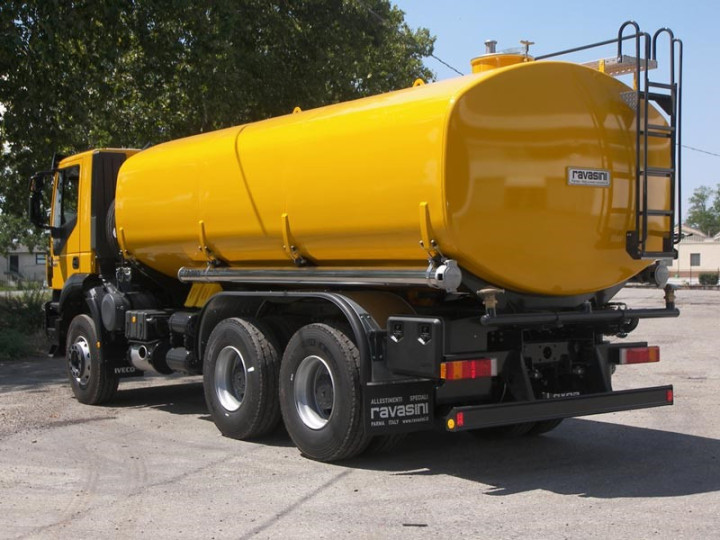 A yellow vacuum tanker truck with cylindrical tank and rear ladder, parked on a paved surface near trees. Sewer services to suction out the fluid from septic tanks from ayahkutub.com.